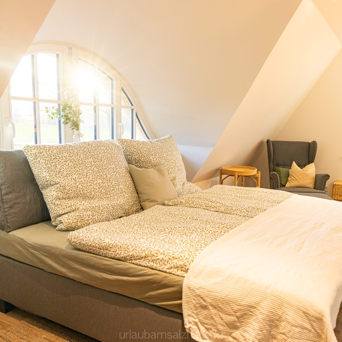 Doppelbett und Sitzgelegenheit in einem hellen Schlafzimmer
