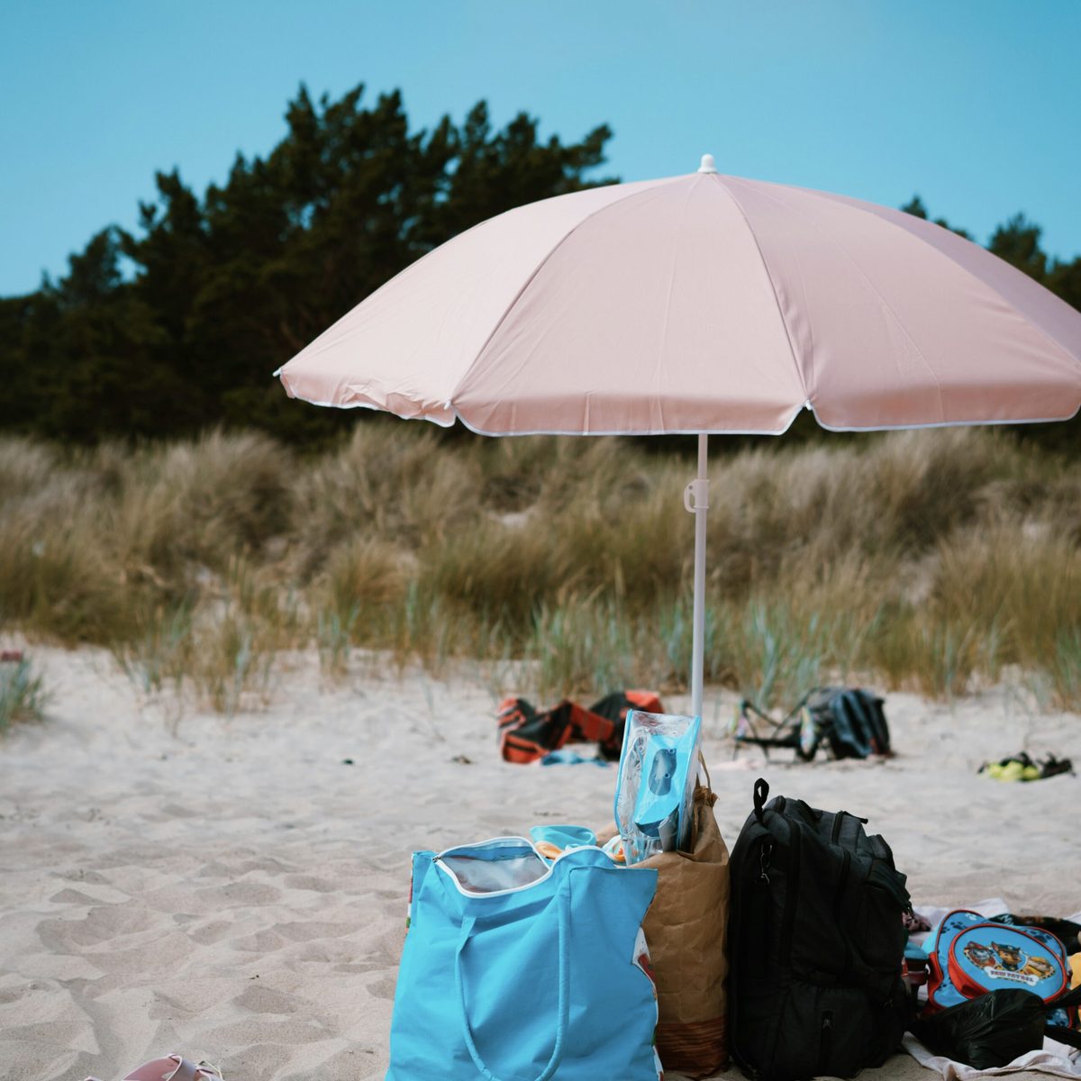 Sonnenschirm und Familiengepäck auf einem kinderfreundlichen Strand