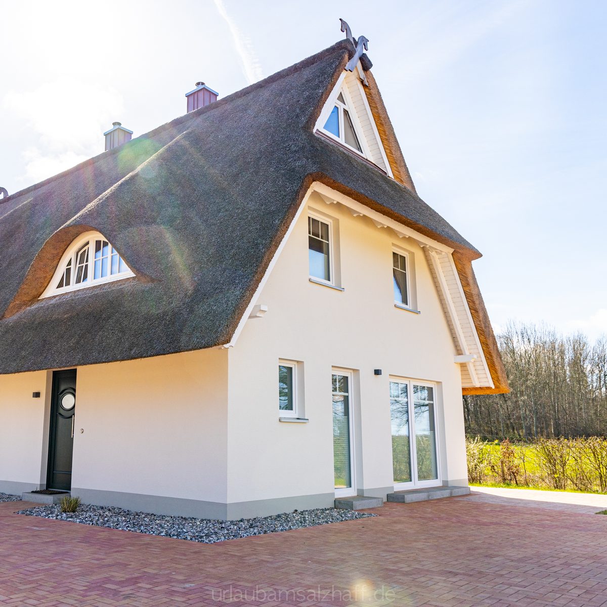 Charmantes Reetdachhaus unter sonnigem Himmel, bereit für deinen Einzug.
