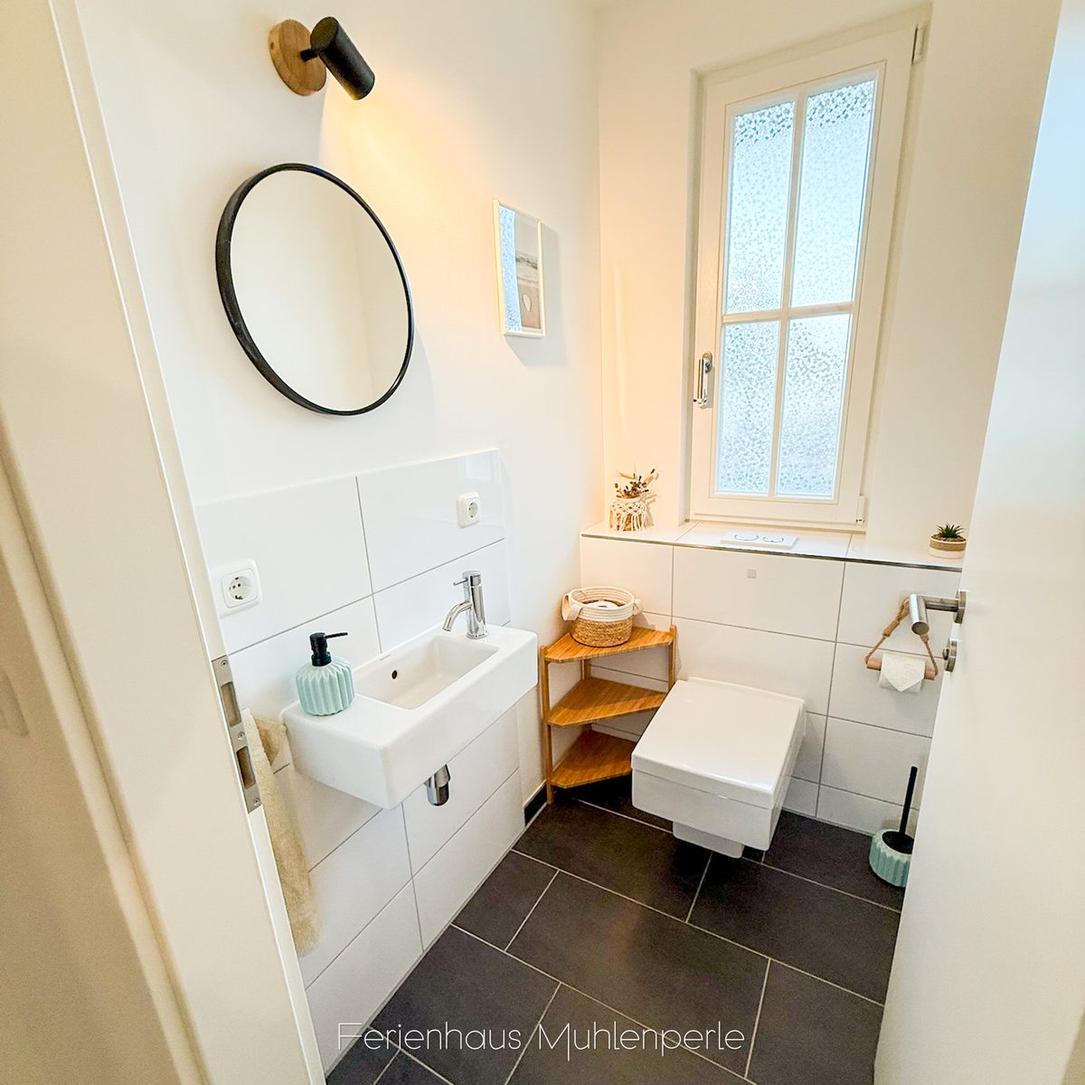 Gästetoilette mit Waschtisch und Spiegel im Ferienhaus Mühlenperle
