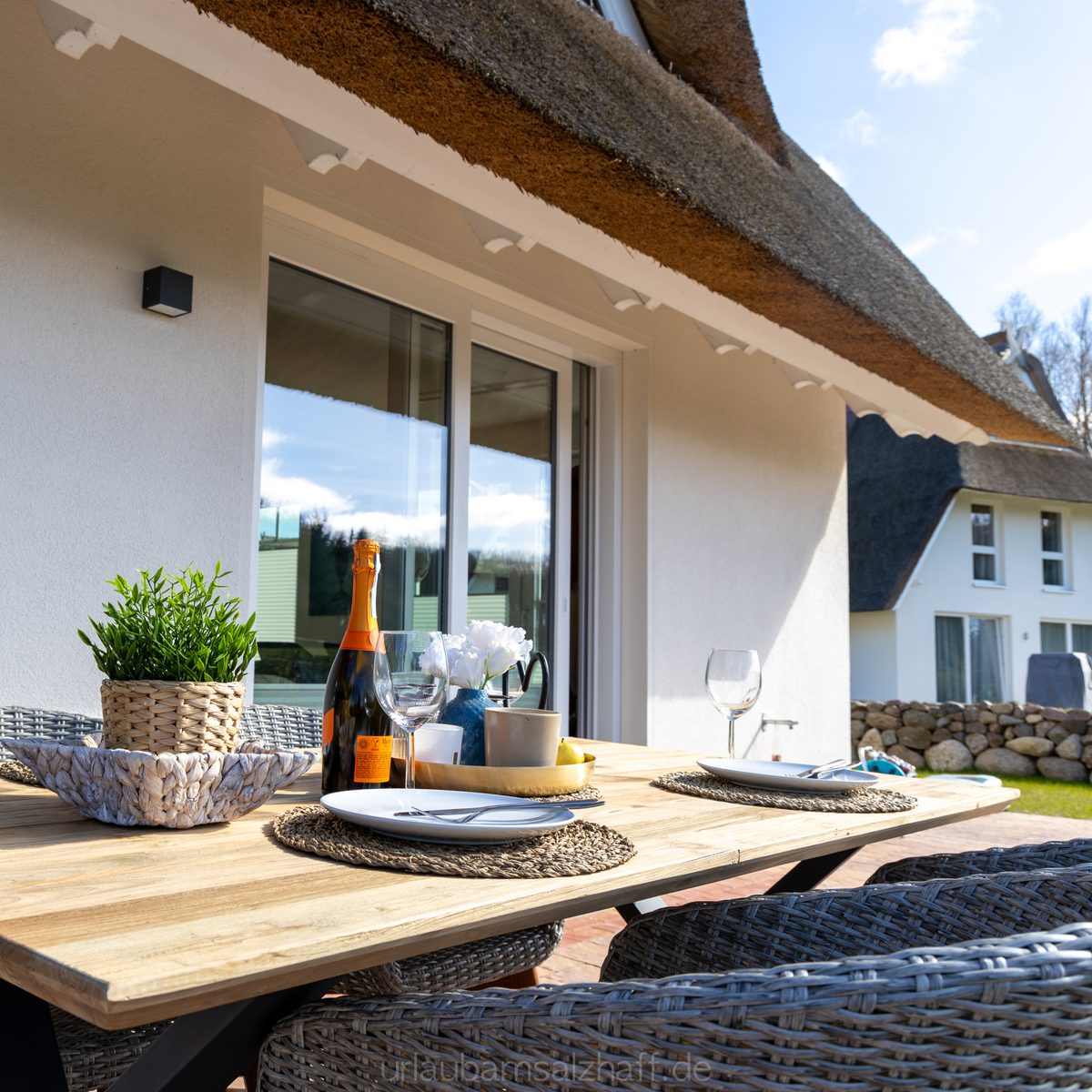 Gedeckter Tisch auf der Terrasse unter dem Reetdach